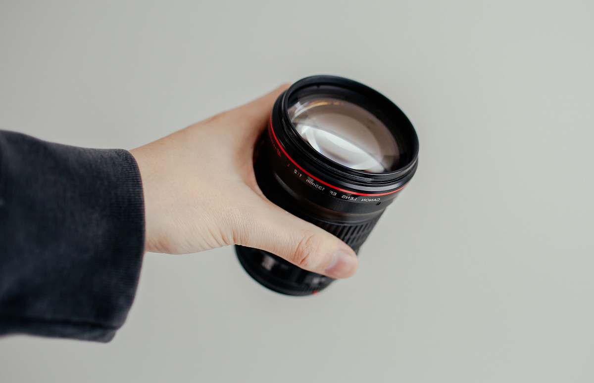 caucasian person holding black camera lens hold