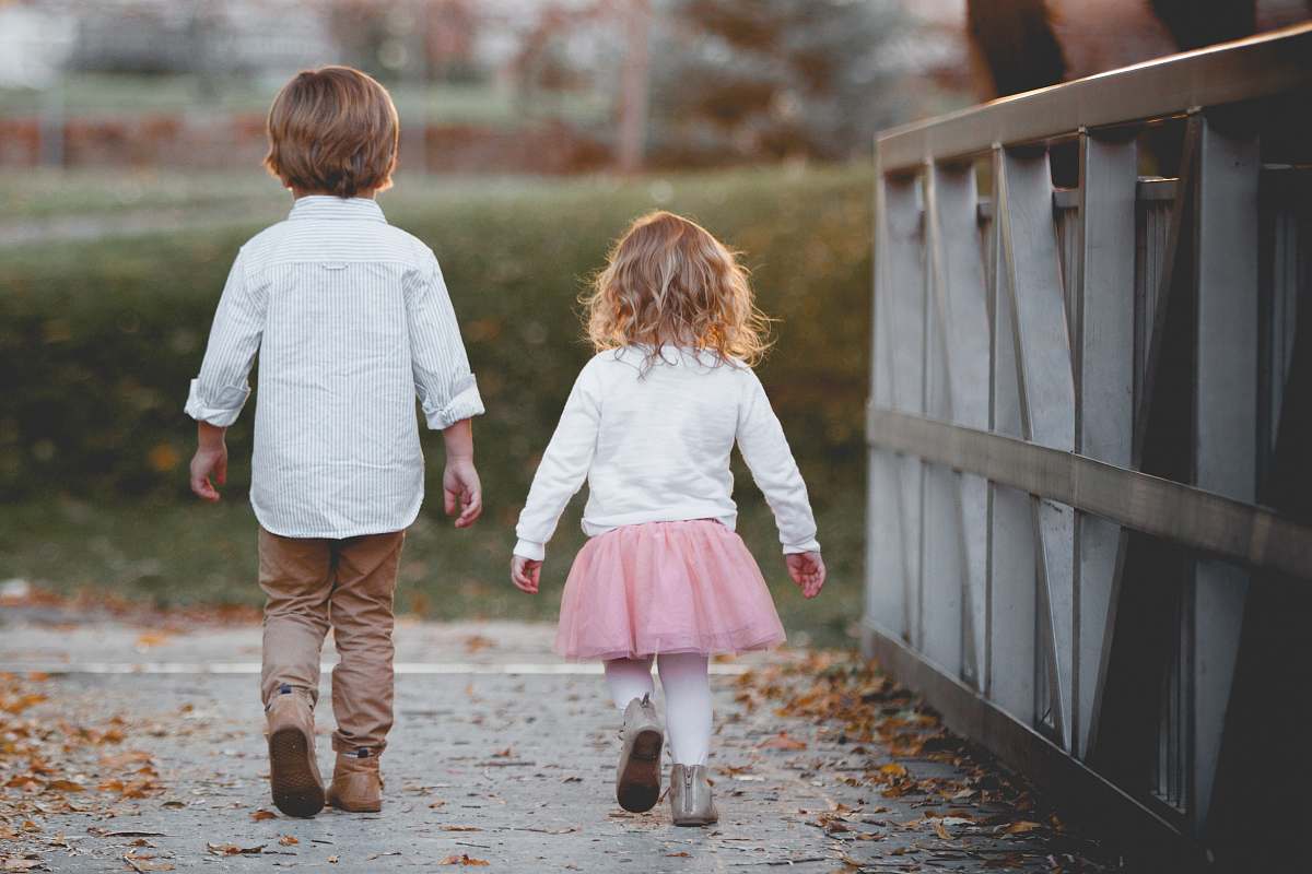 person boy beside girl walking near railing people
