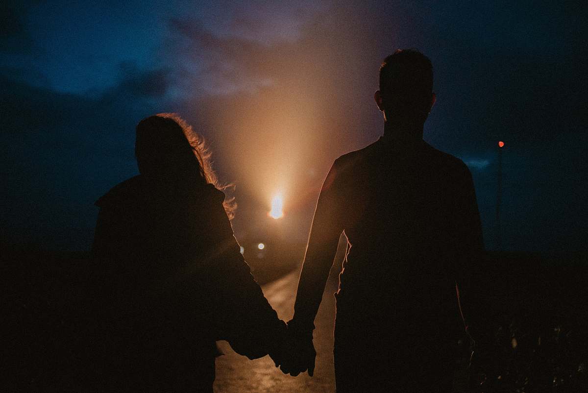 person gray-scale photo of man and woman holding hands flare