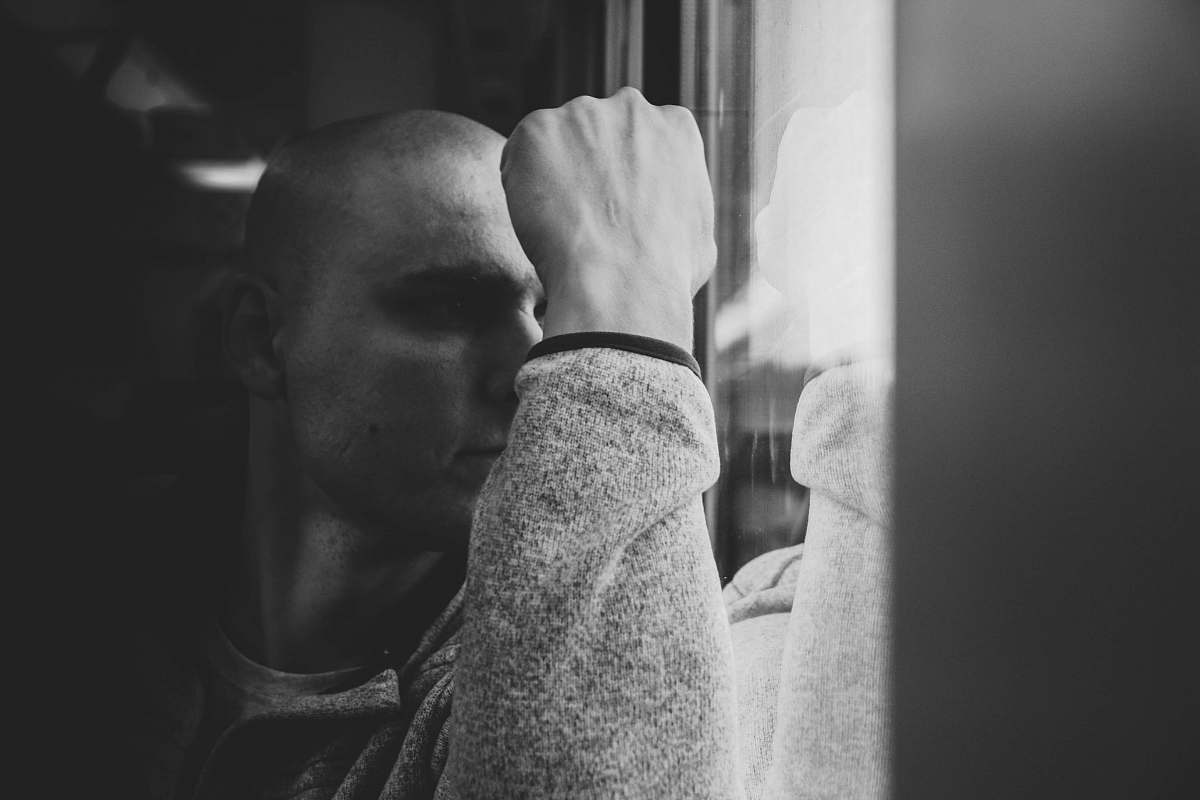 black-and-white grayscale photo of man sitting beside vehicle window seat grey