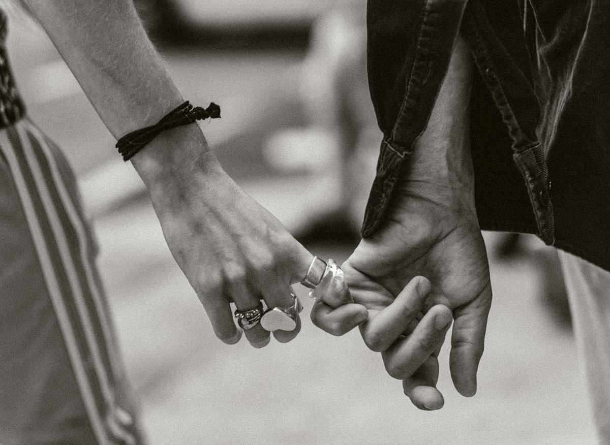 person grayscale photography of couple holding hands while walking holding hands