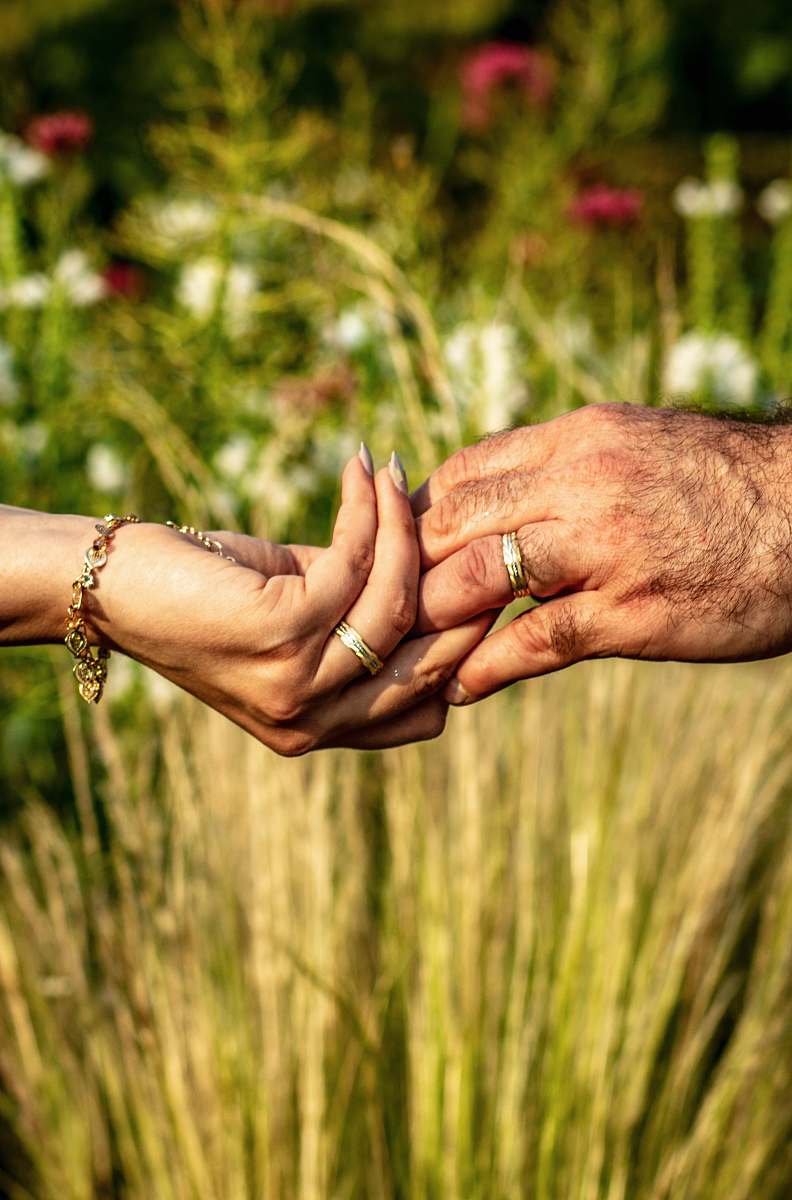 person holdings hands with gold-colored ring over flower garden hand