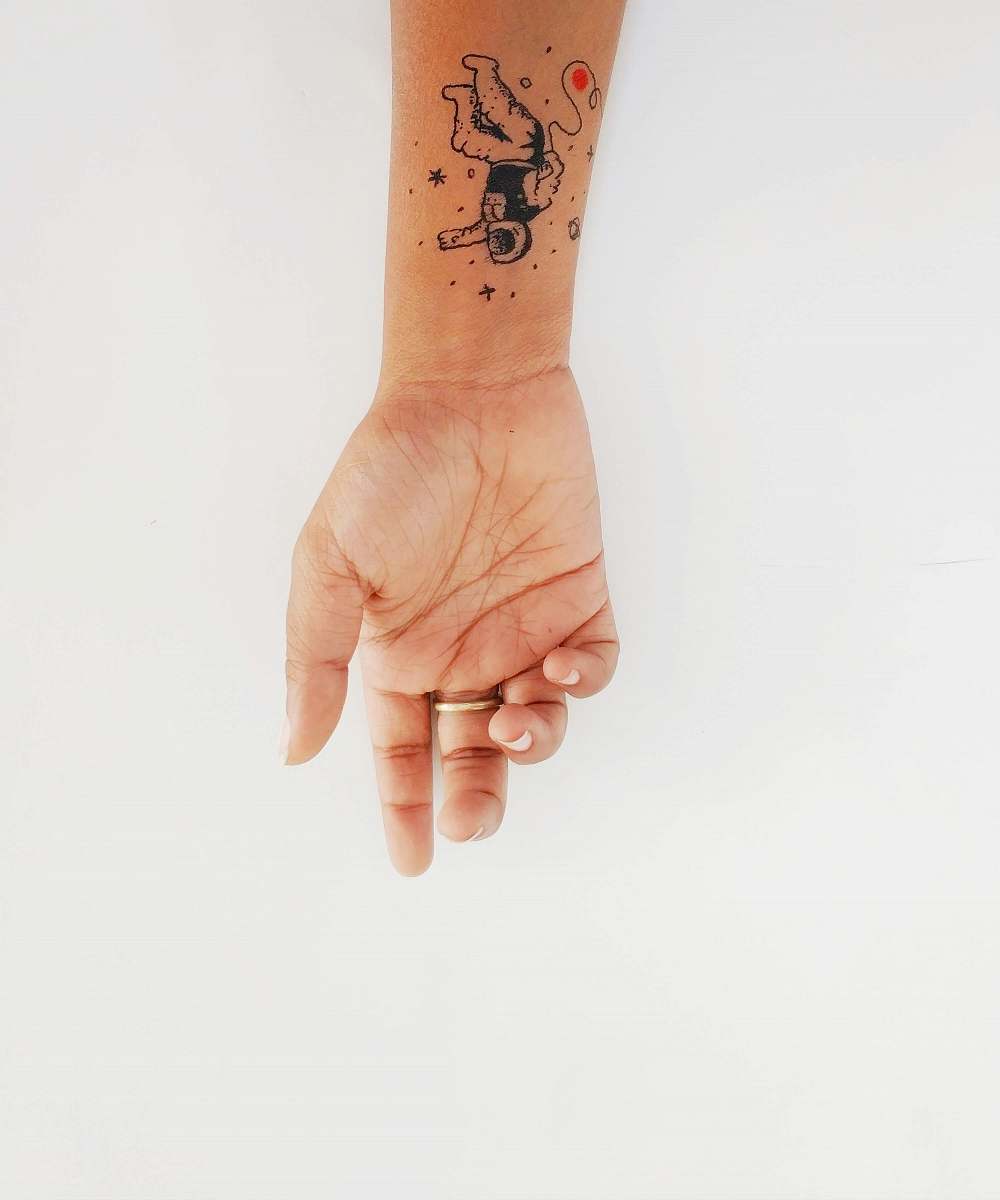 skin human hand with astronaut tattoo brown