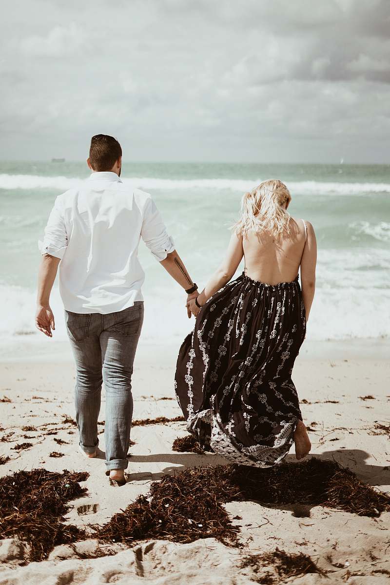 person man and woman on white sand apparel