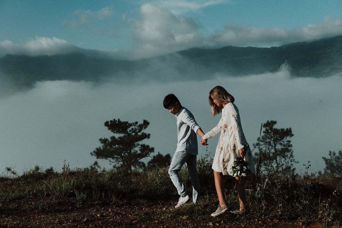 person man and woman walking while holding hands clothing