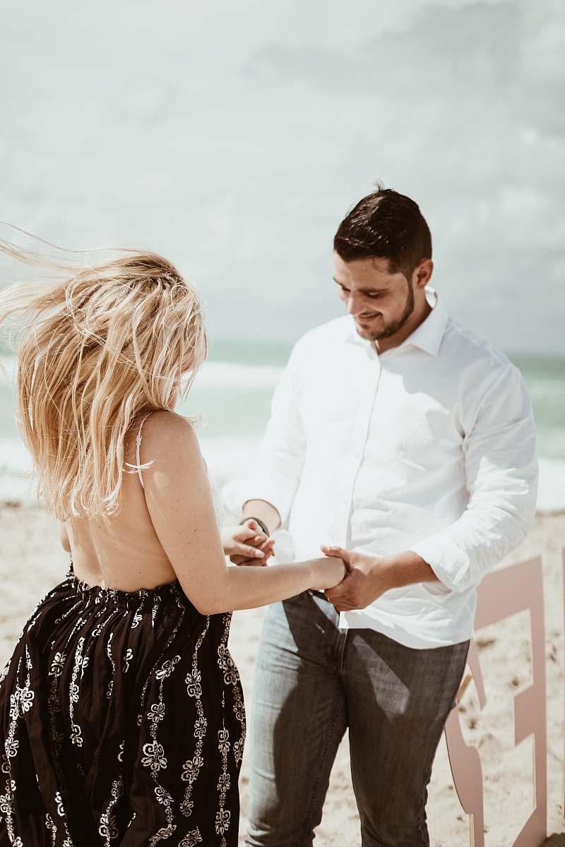 Capture the essence of love and connection with this stunning image of a couple sitting on a picturesque beach, hands raised in celebration. The warm glow of the sunset casts a romantic ambiance, making it perfect for wedding invitations, relationship blogs, or travel photography. This heartwarming scene symbolizes unity and the joy of companionship, ideal for projects focused on romance, adventure, or lifestyle themes.