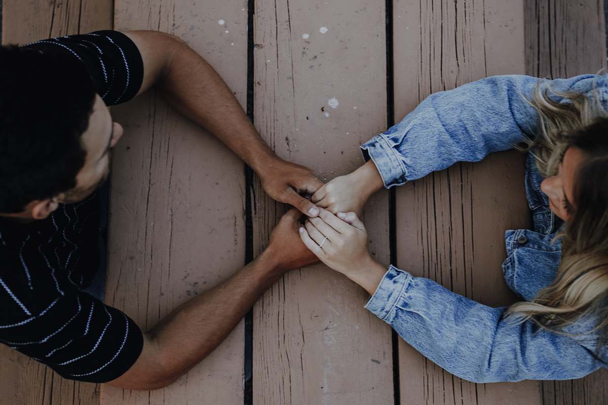 person man holding woman's hands pants