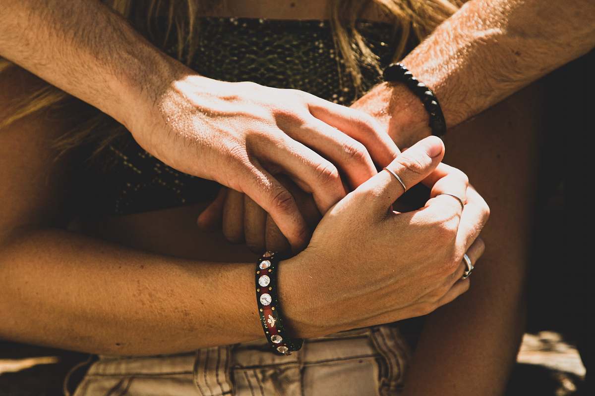 person man hugging woman behind her back hand