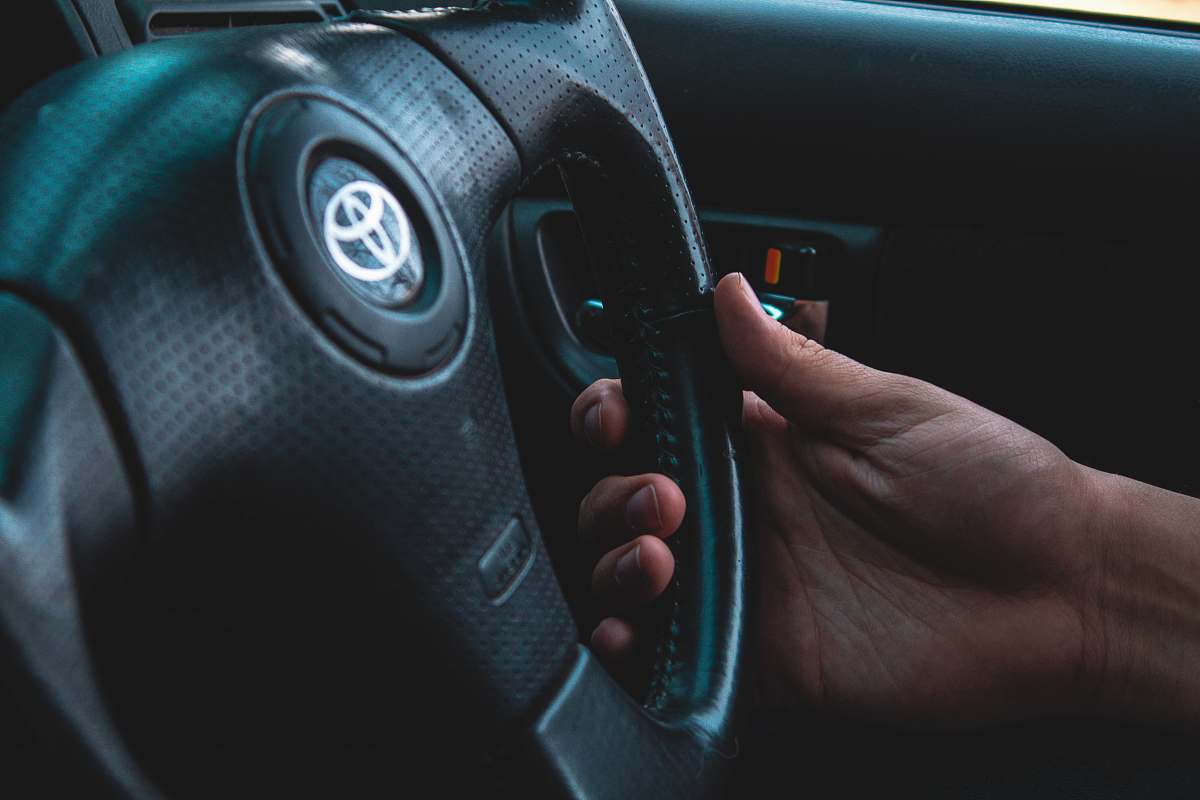 person person holding black Toyota vehicle steering wheel steering wheel