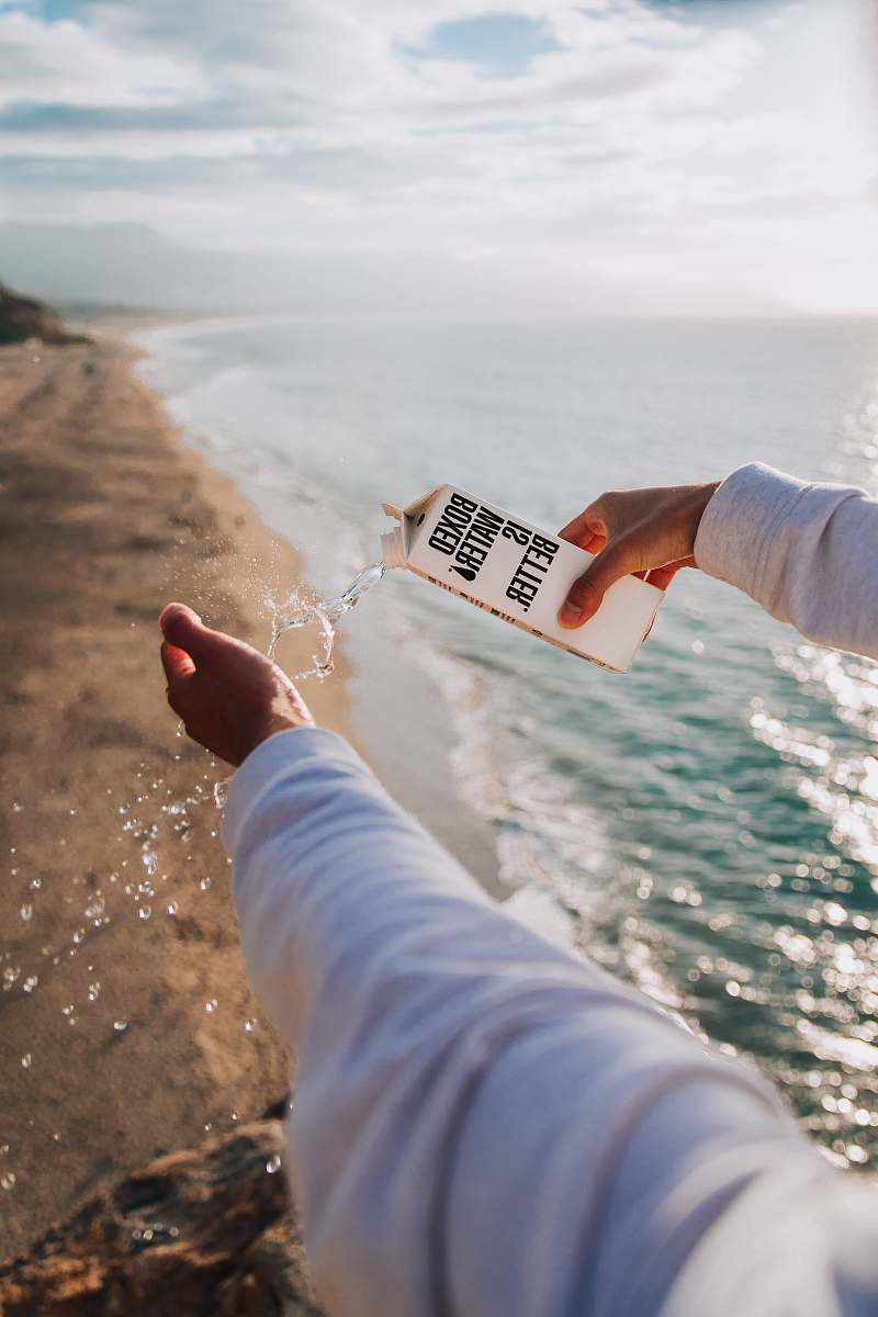 person person holding boxed water across seashore boxed water