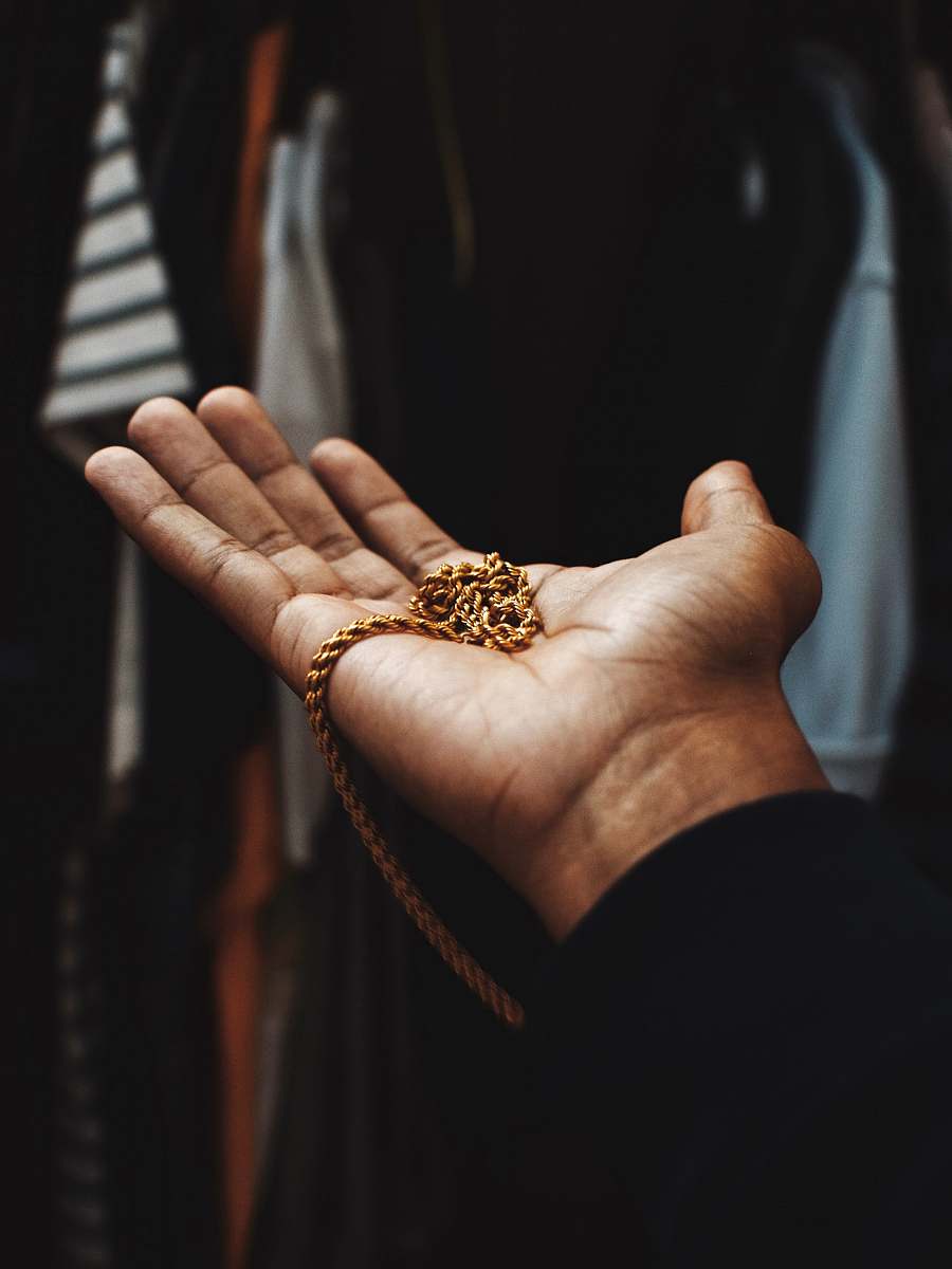 person person holding chain gold-colored necklace finger