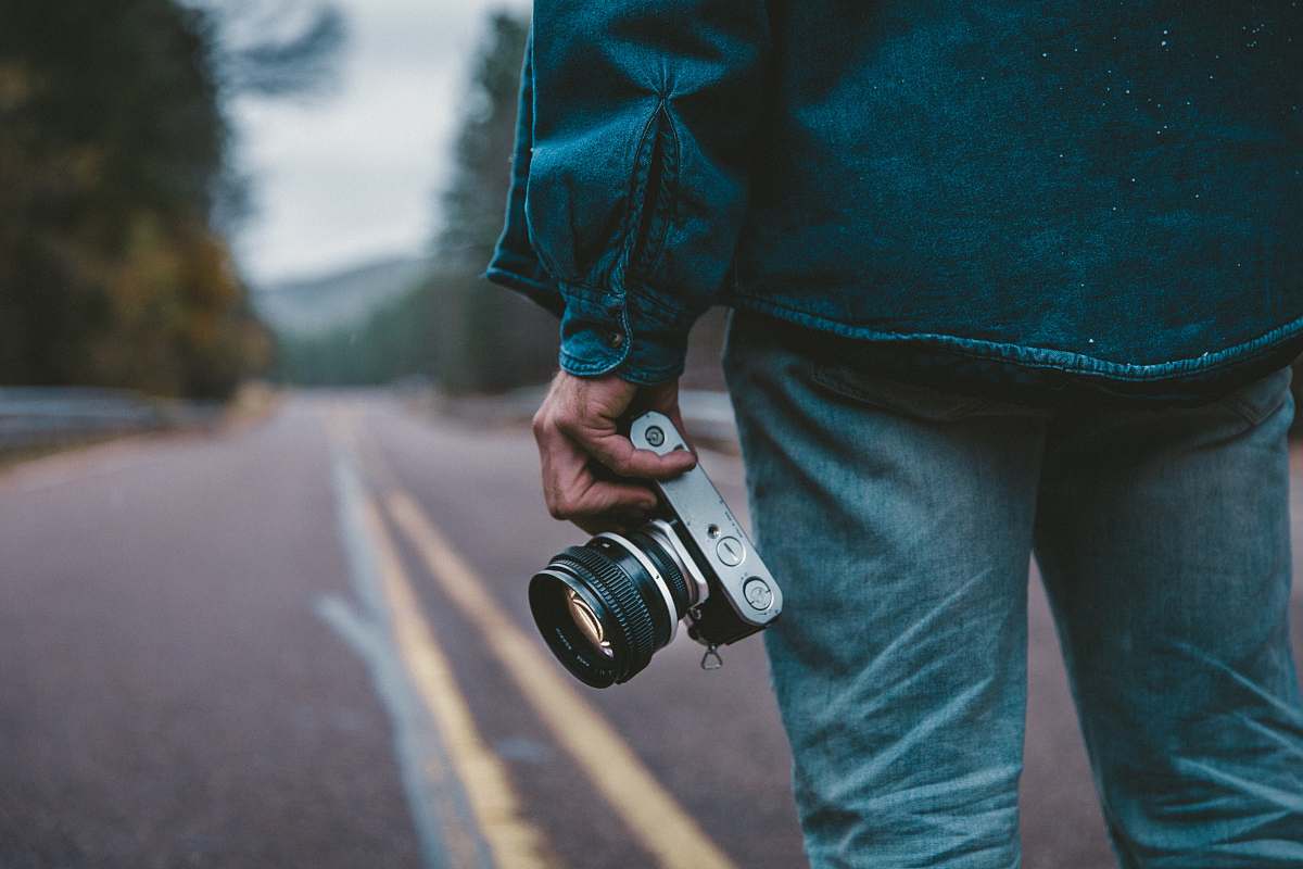 person person holding gray and black camera while standing on road camera