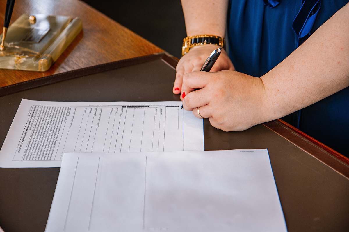 person person holding pen and writing on paper wristwatch