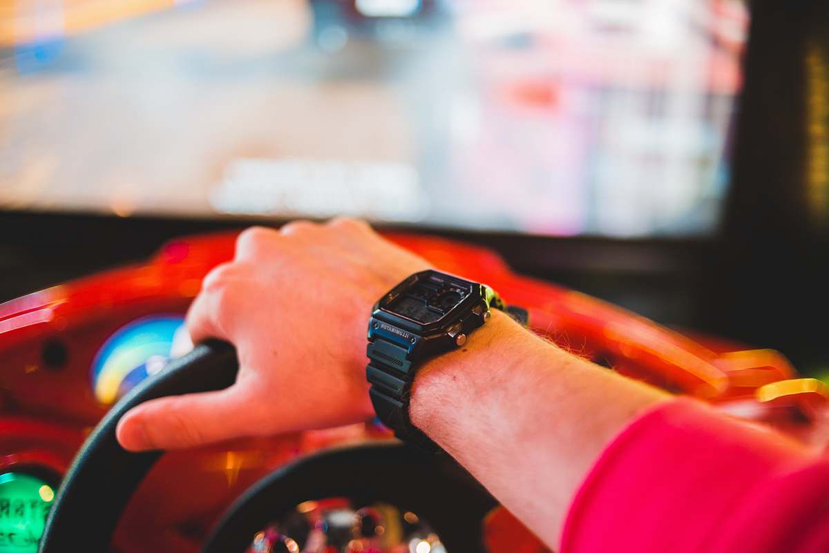 wristwatch person playing arcade driving game person