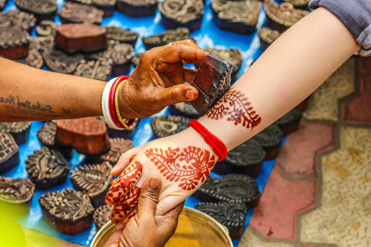 person person putting menhdi tattoo on woman's arms tattoo