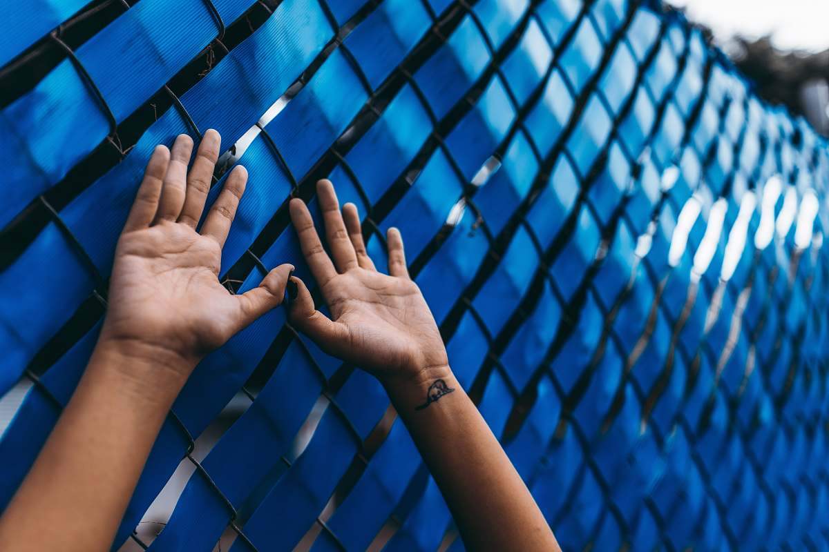 hand person raising their arms beside blue wall finger