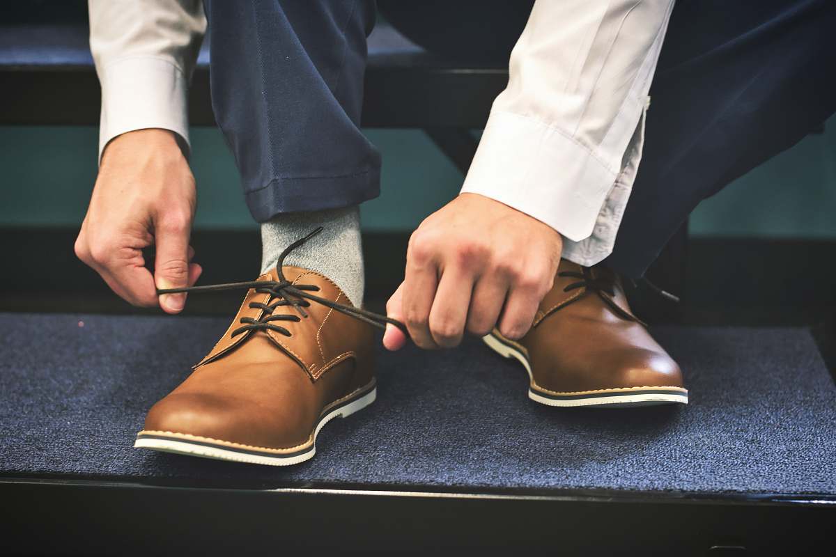 person person tying brown leather shoes people