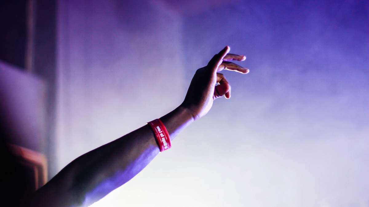 person person with red silicone band raising right hand arm