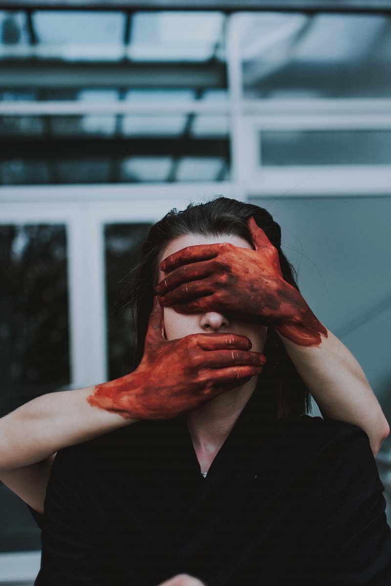 person red painted hands holding woman's face finger