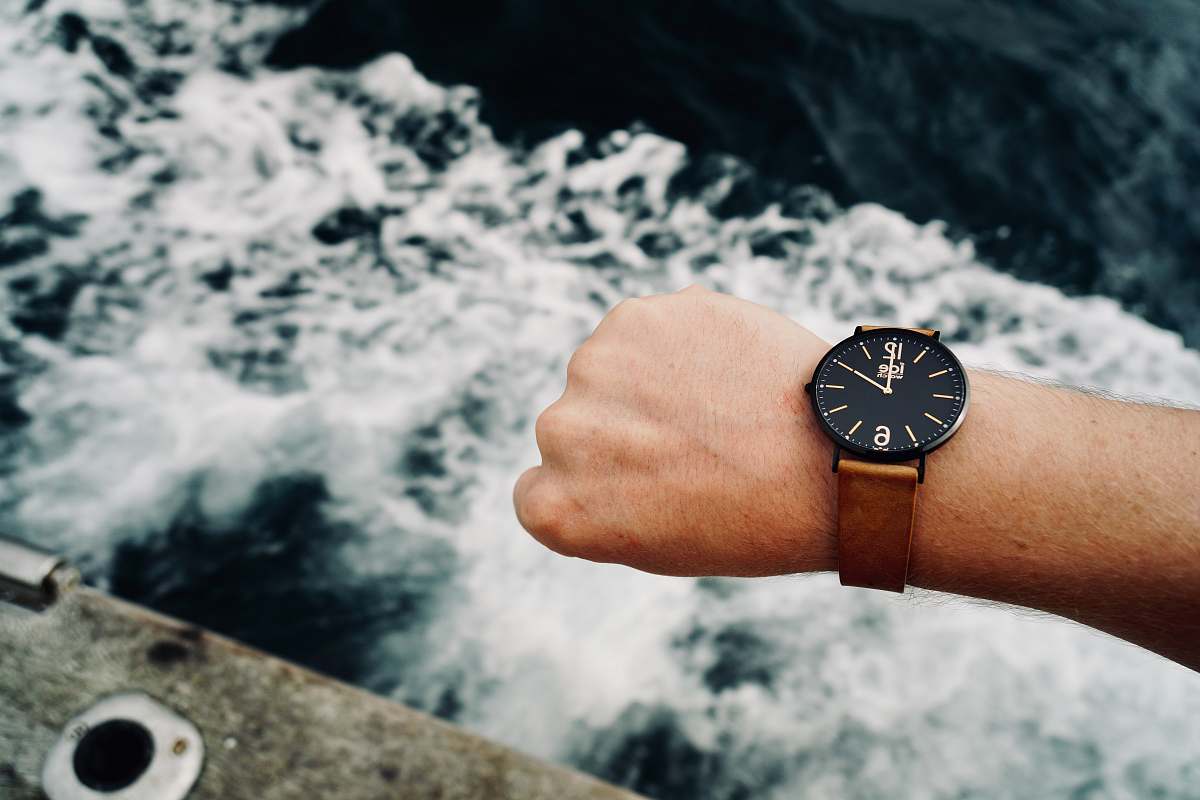 person round black analog watch with brown band wristwatch