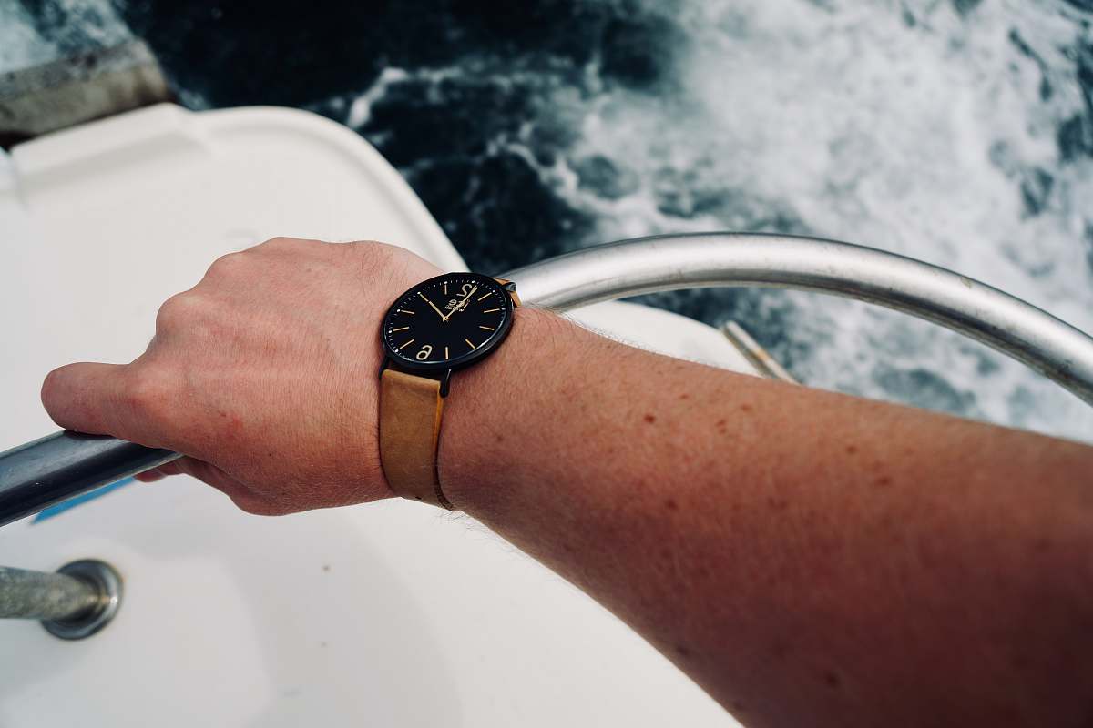 person round black analog watch with brown leather band wristwatch
