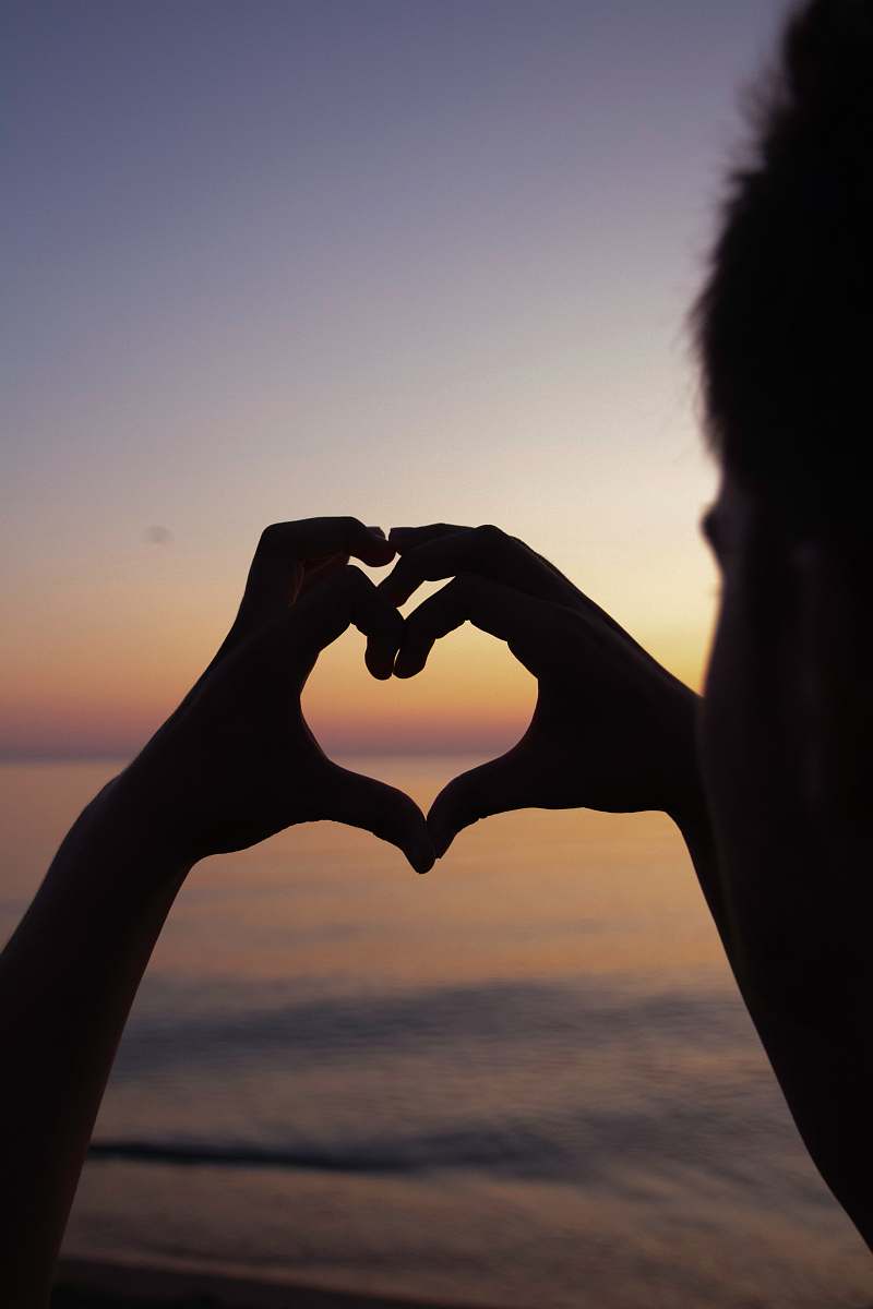 hand silhouette of person doing heart handsign finger