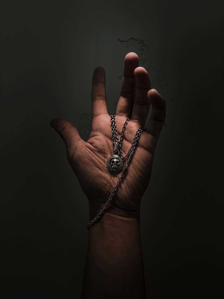 person silver-colored pendant necklace finger