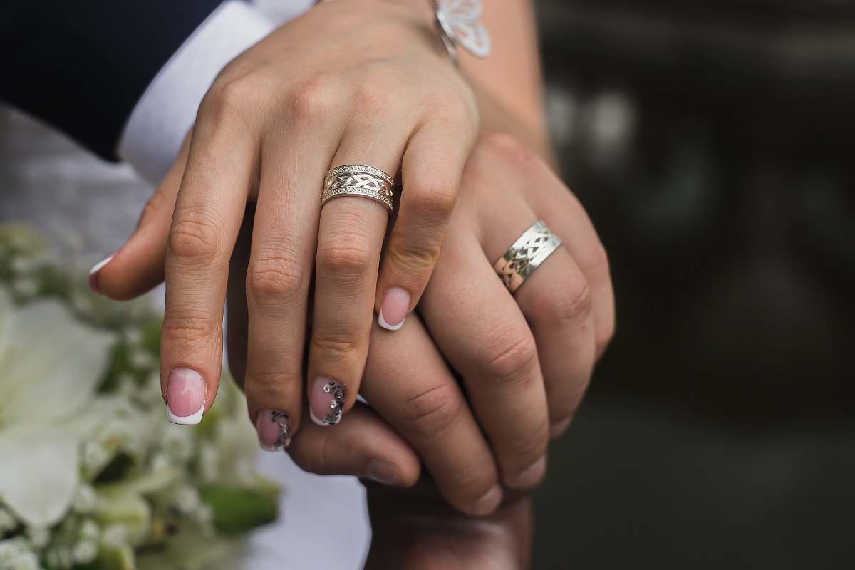 person silver-colored wedding rings finger