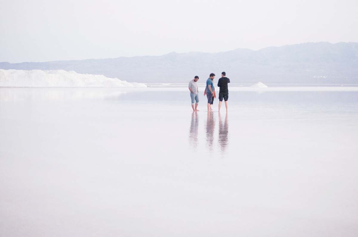 person three men standing on shore standing