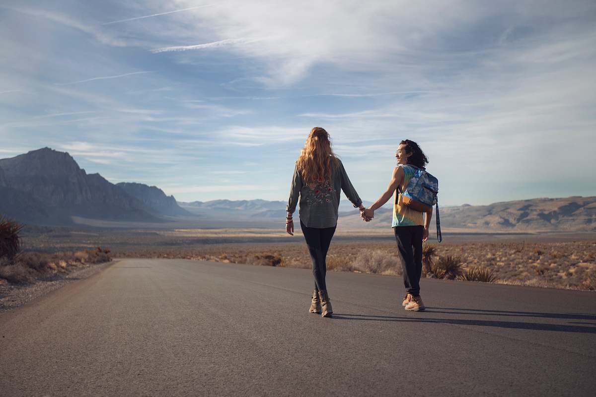 person two man and woman walking on asphalt road walking