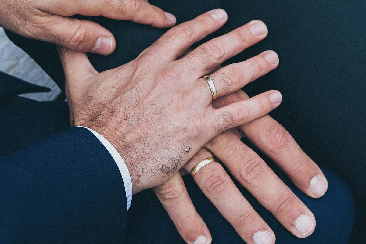person two man's hands wearing gold-colored wedding rings people