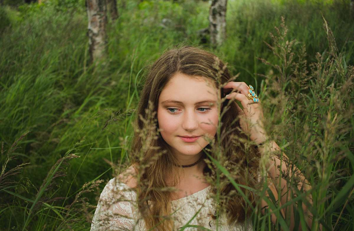 face woman brushing her hair inside tall grass field grass