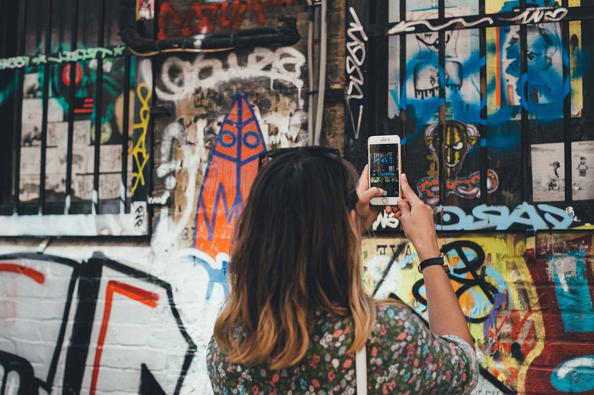 graffiti woman holding phone taking picture at wall phone