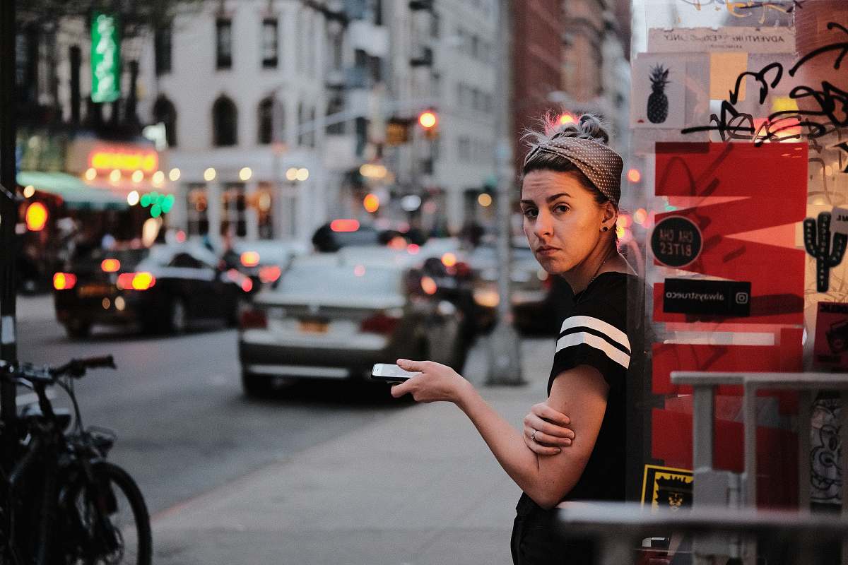 woman woman learning on glass shelf infront on road and buildings girl