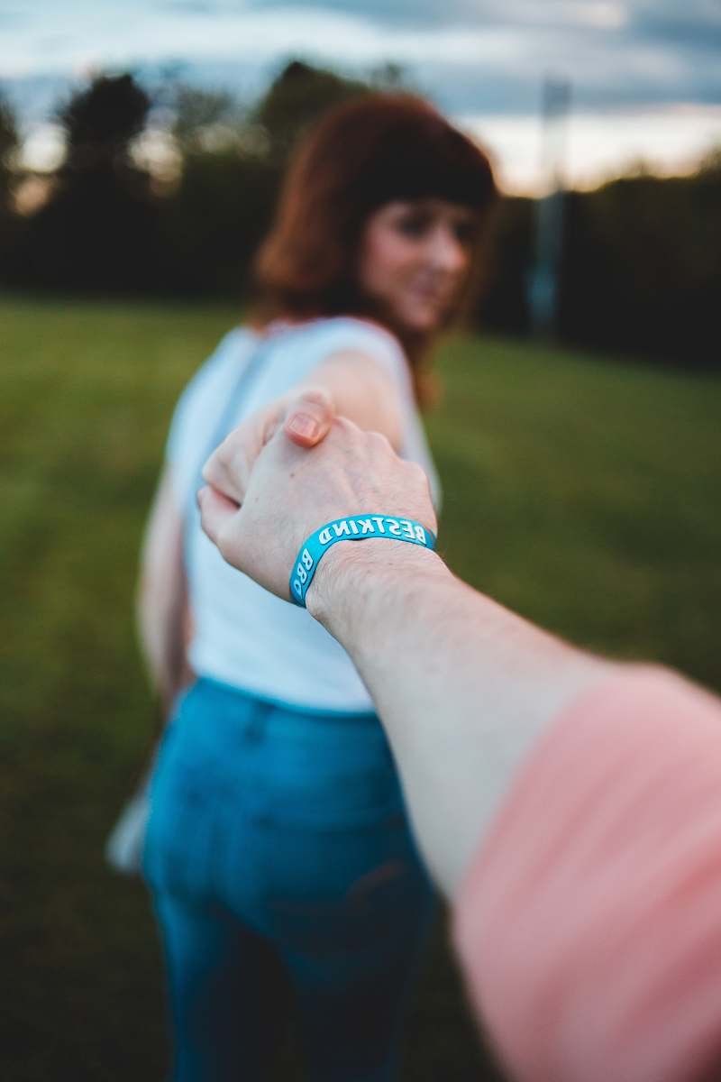 person woman reaching hand of another person while standing on green field hand