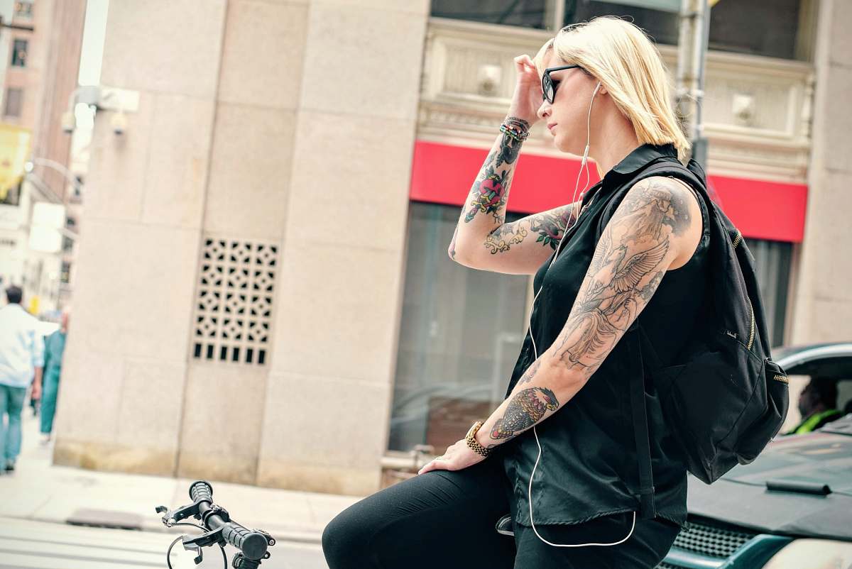 person woman riding bicycle while holding her left face tattoo