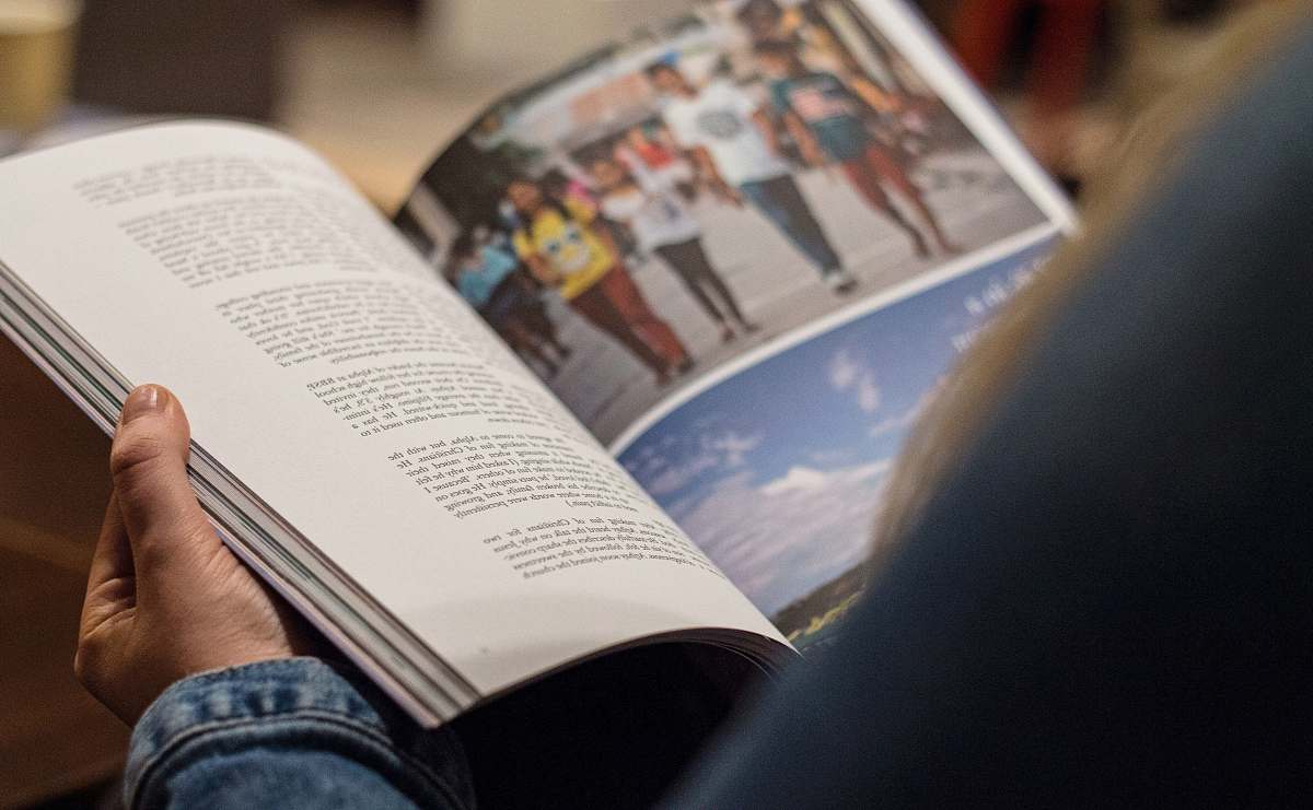 read person in blue denim top reading book book