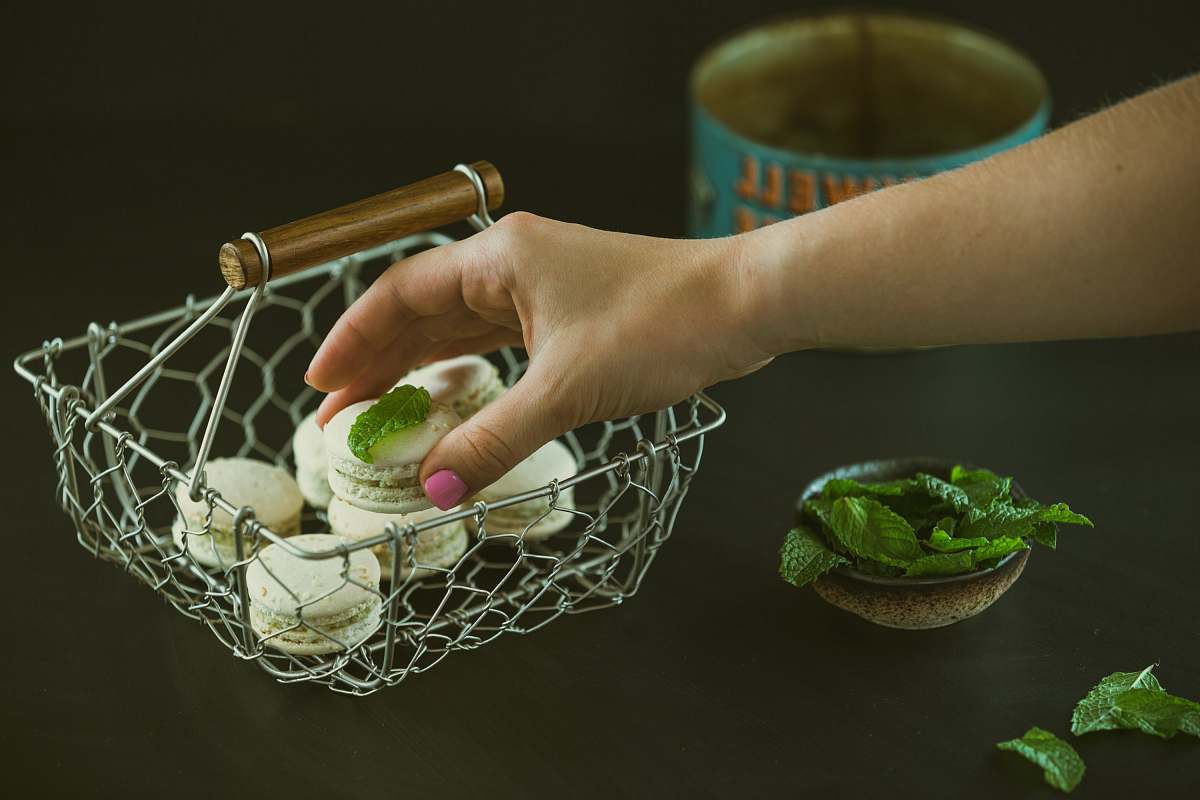 food person holding round cookie near green leaf vegetable pastry