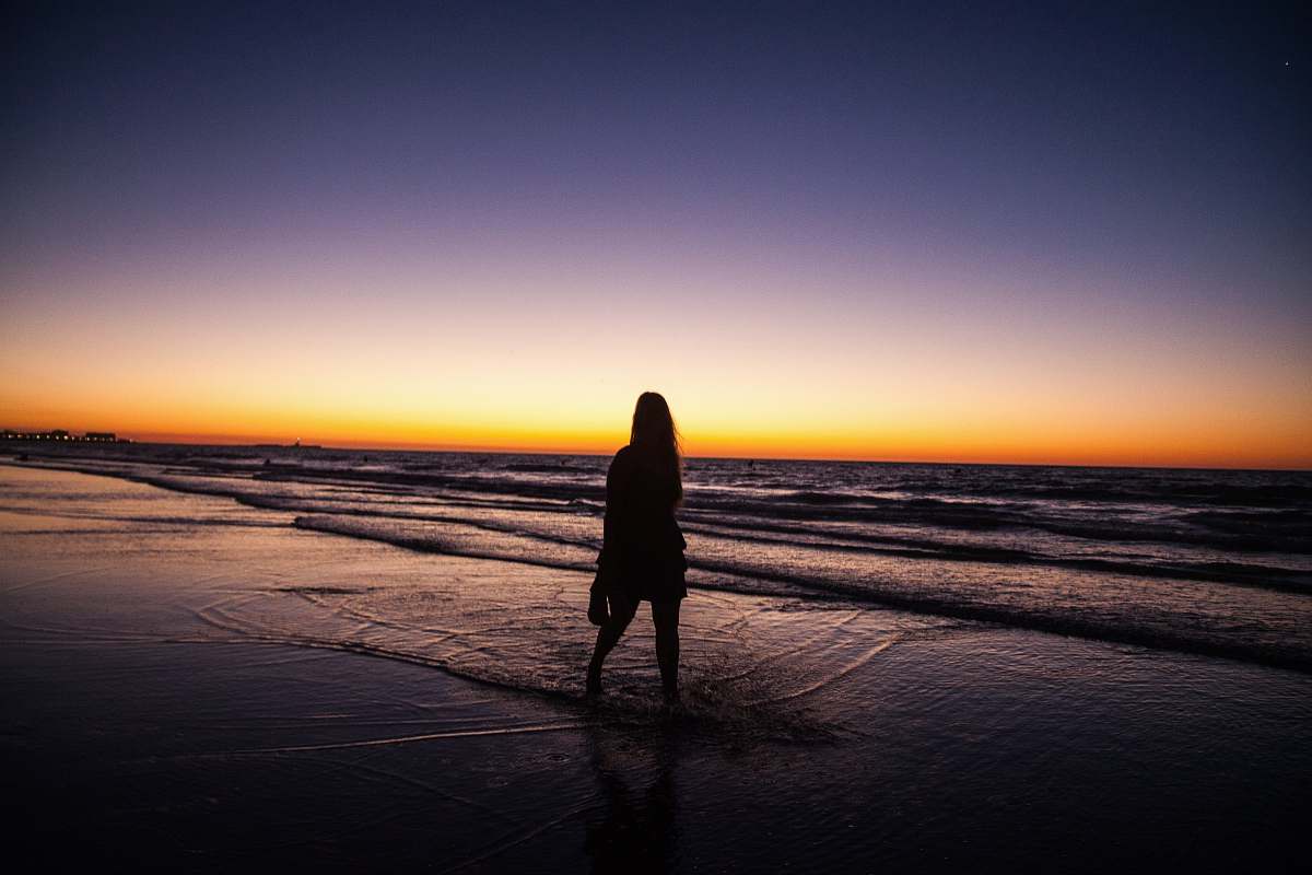 outdoors woman standing by the seashore under the sunset horizon