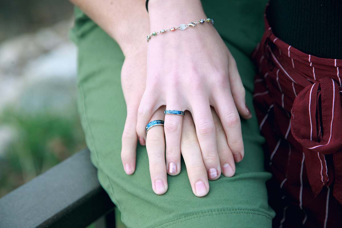 person couple holding hands while sitting on bench human