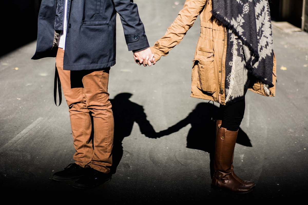 person man and woman standing while holding hands at daytime couple