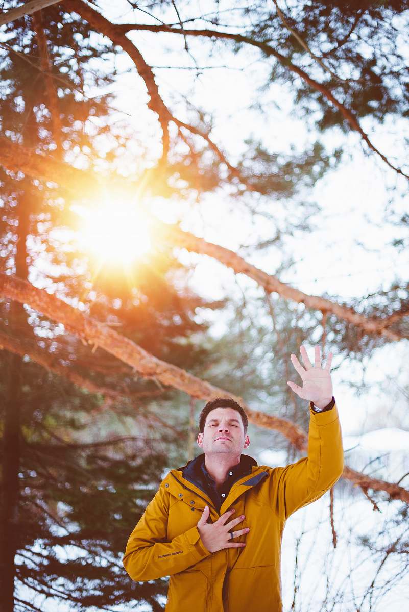 prayer man raising left hand, right hand on chest closed eyes standing outdoor under shade of tree during daytime person