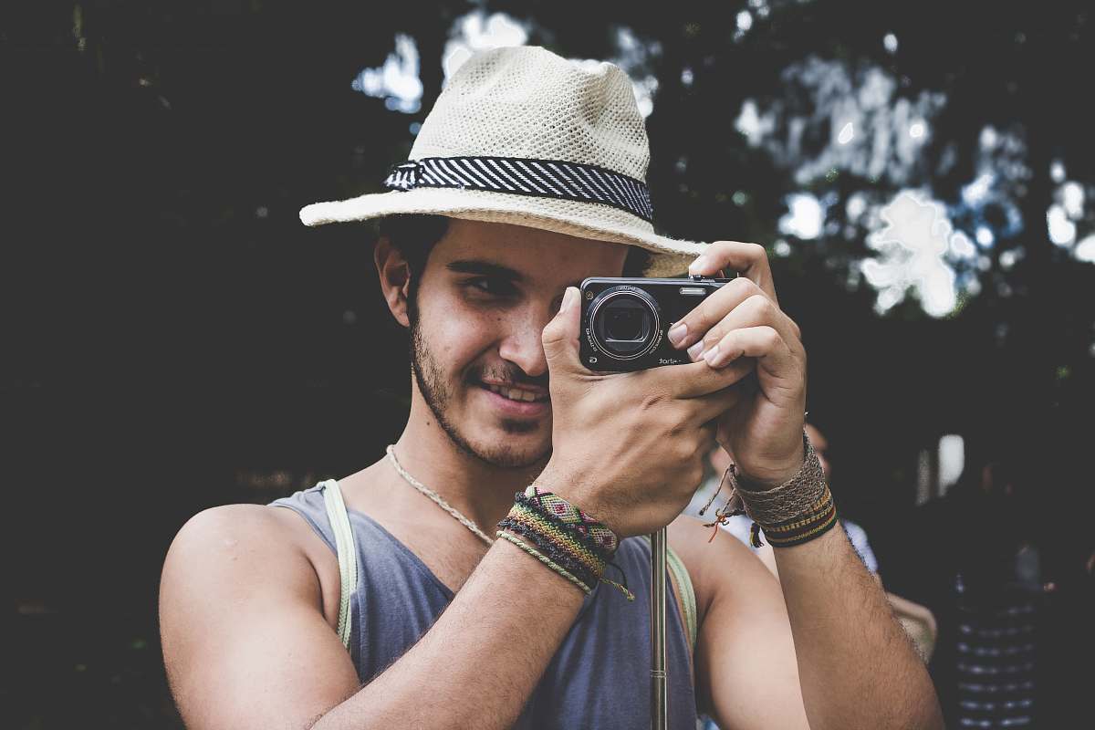 human selective focus photo of man holding black compact camera person
