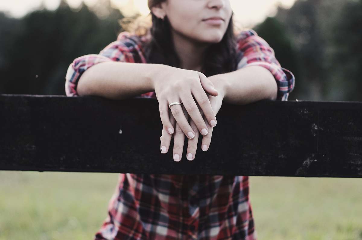 human woman placed her two hands on wooden fence during daytime person