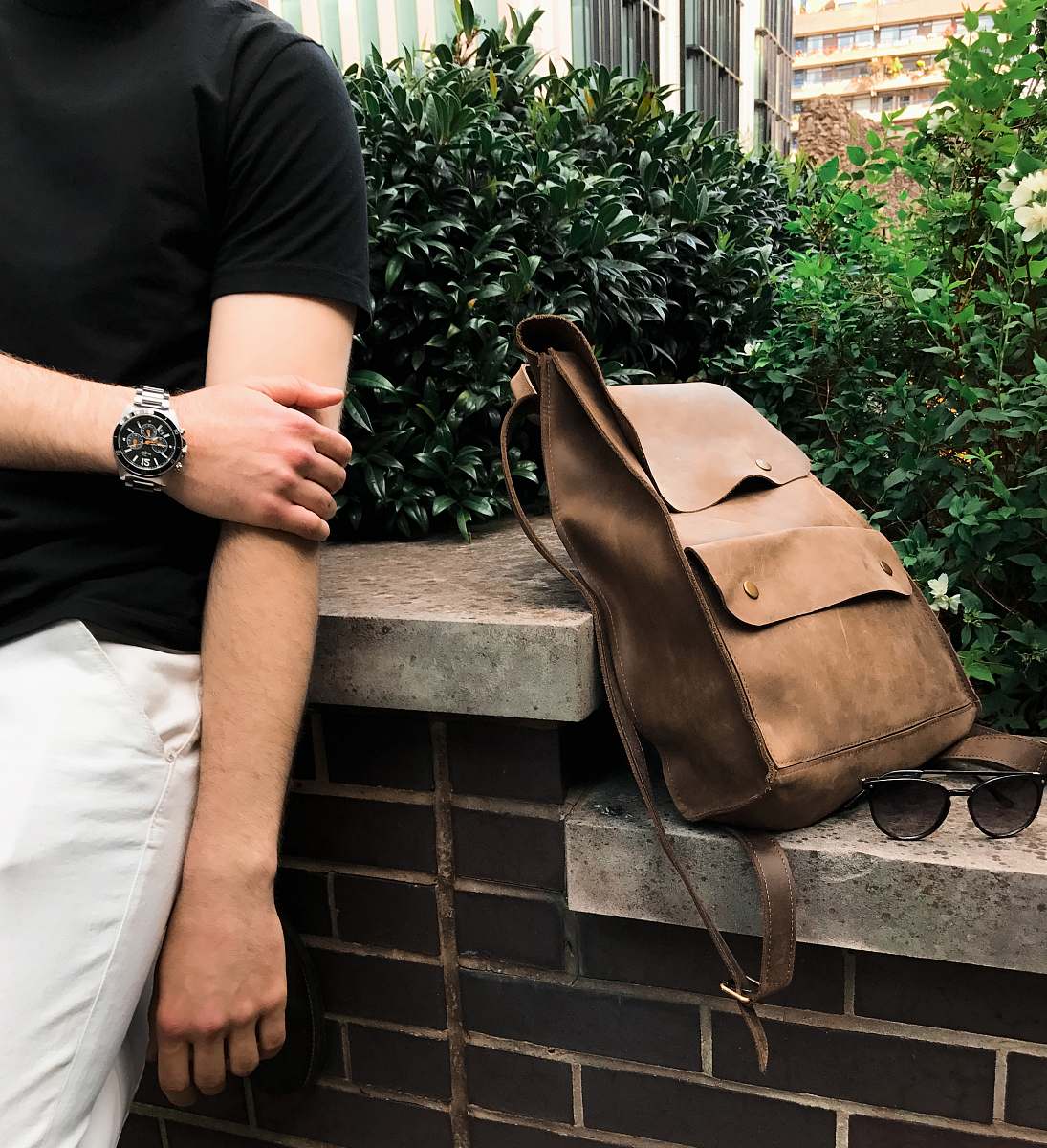 human bag on surface near sunglasses with plants on back people