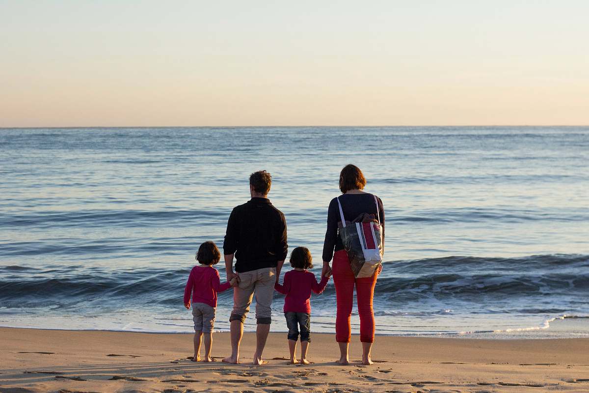 human family of four standing at the seashore outdoors