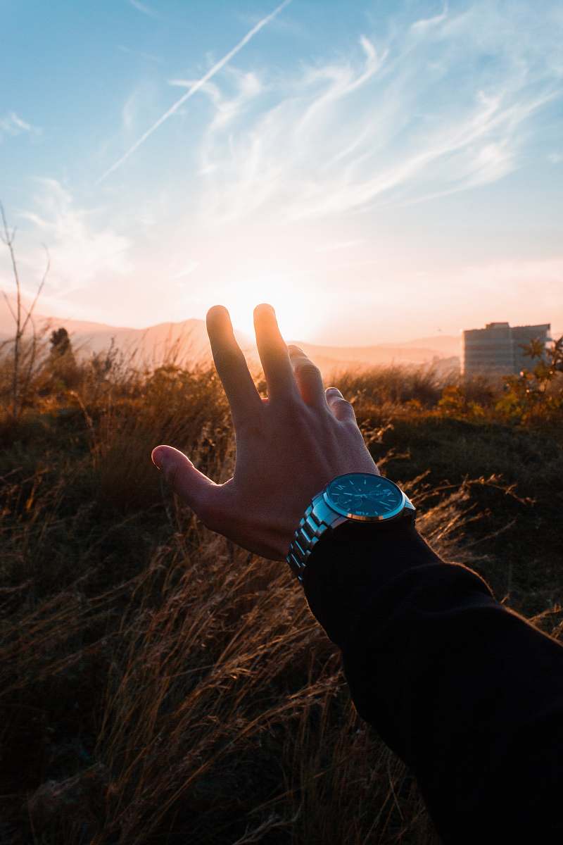 human force perspective photography of person holding sun wristwatch