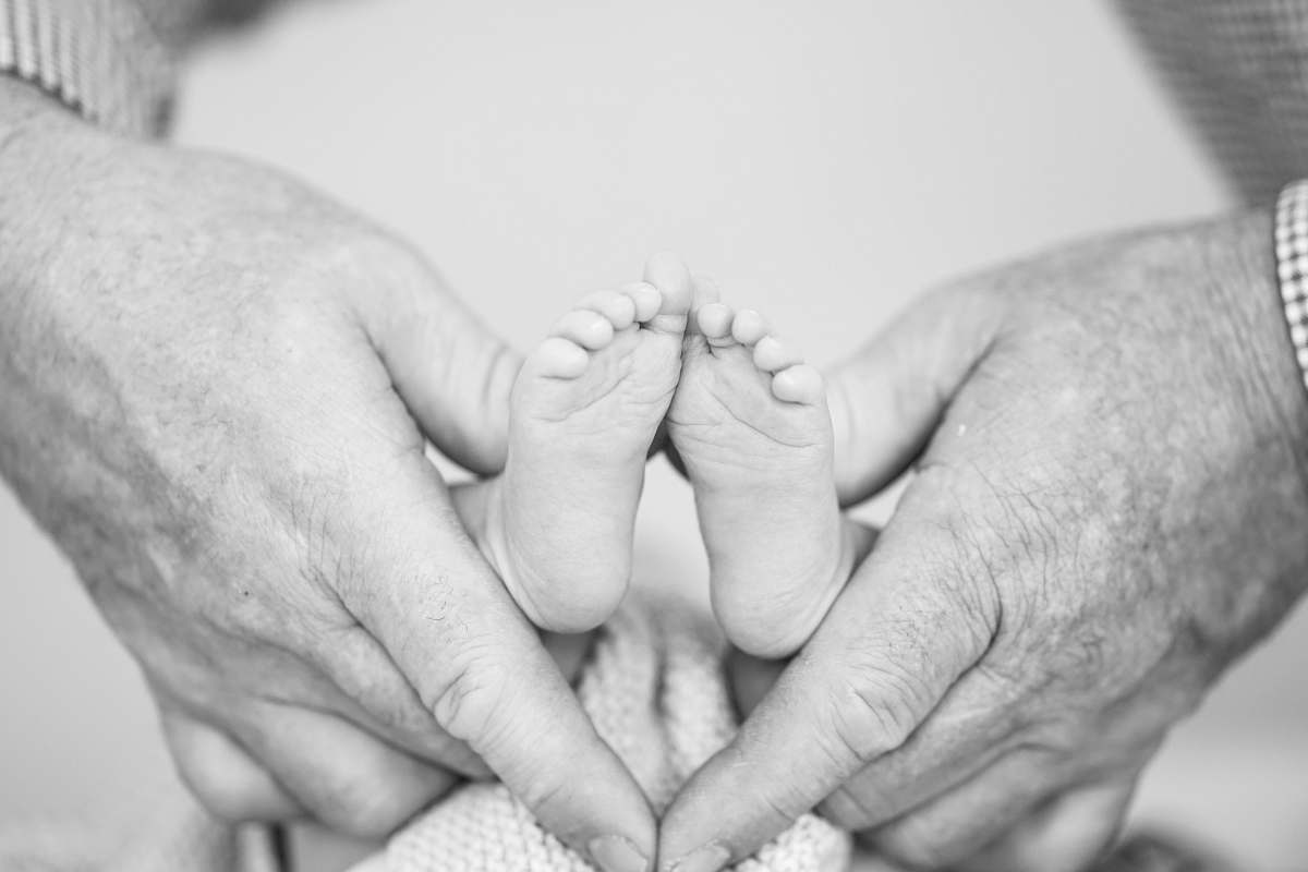 black-and-white grayscale photography of person holding newborn's feet grey