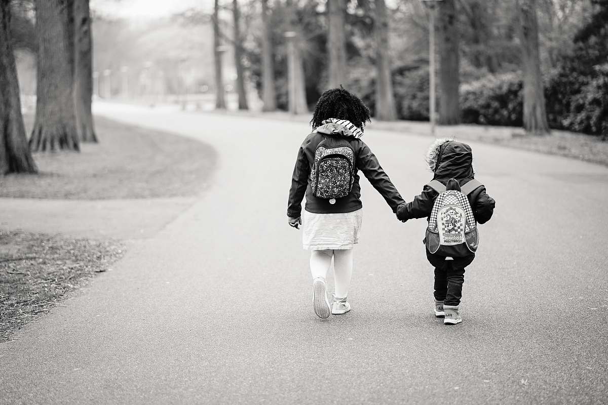 black-and-white grayscale photography of two toddlers walking on road walking