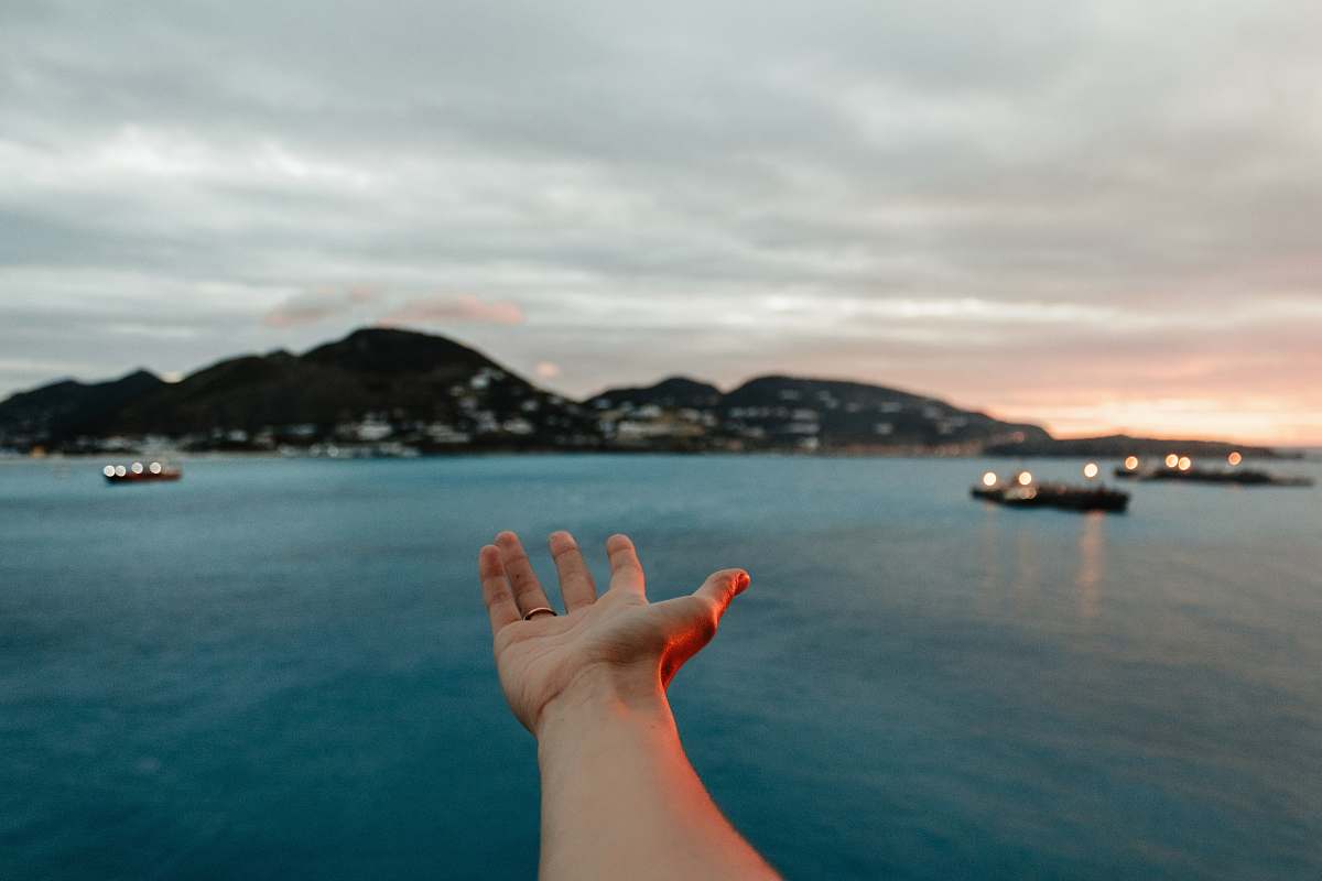 human hand across body of water boat